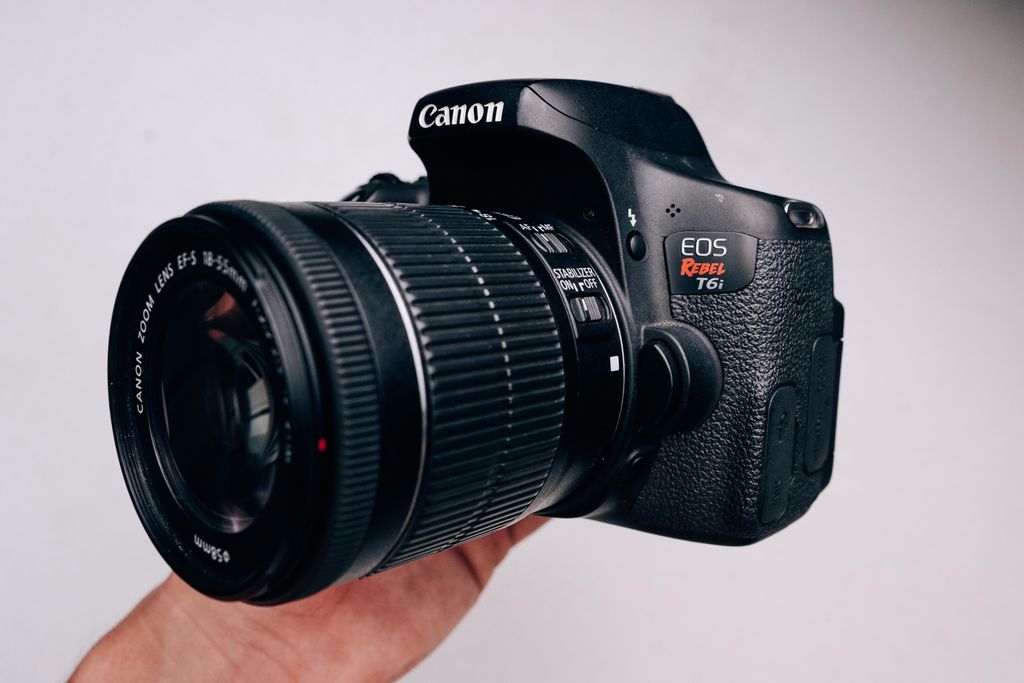 A close-up of a DSLR camera being held, showcasing its body and lens details.
